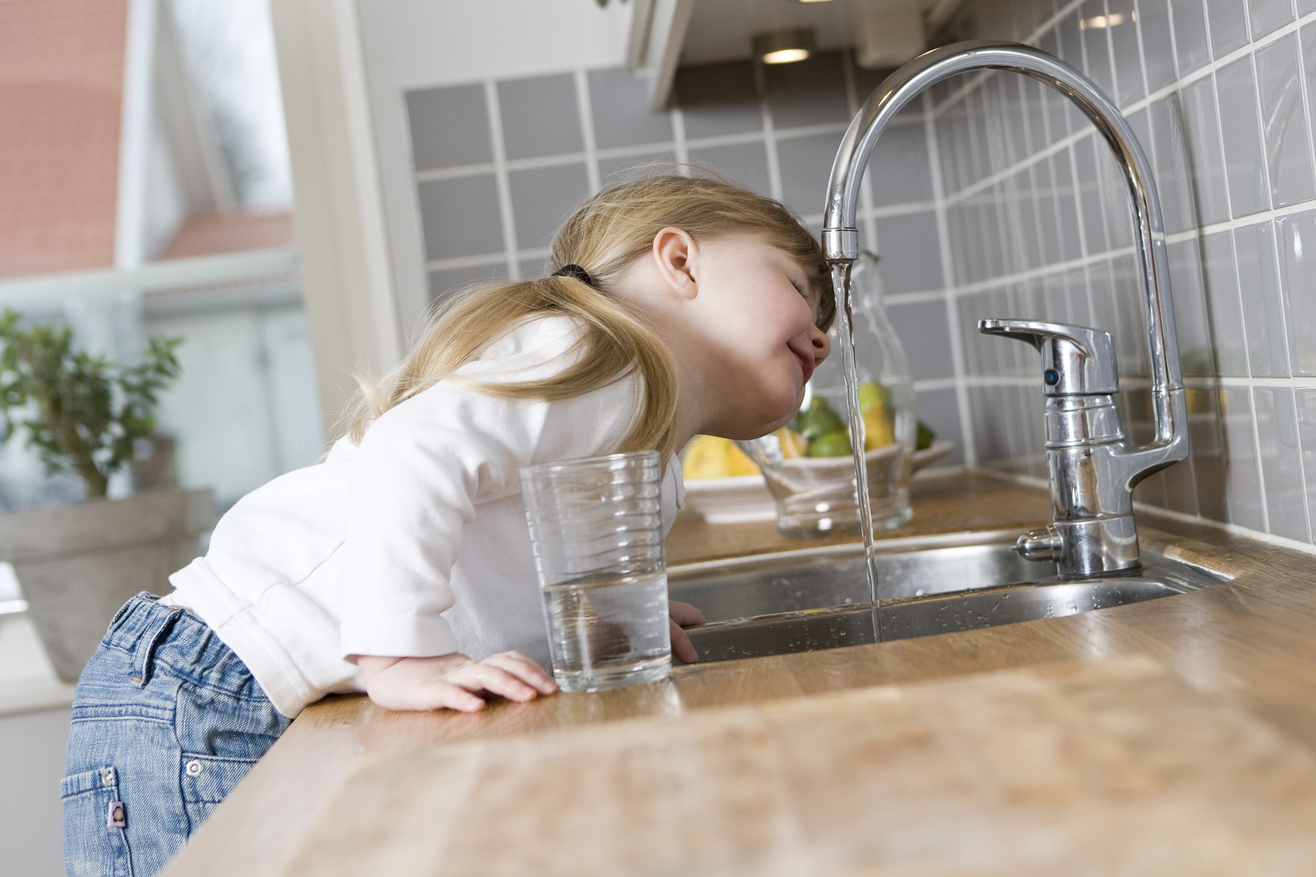小女孩在厨房里用水龙头喝水