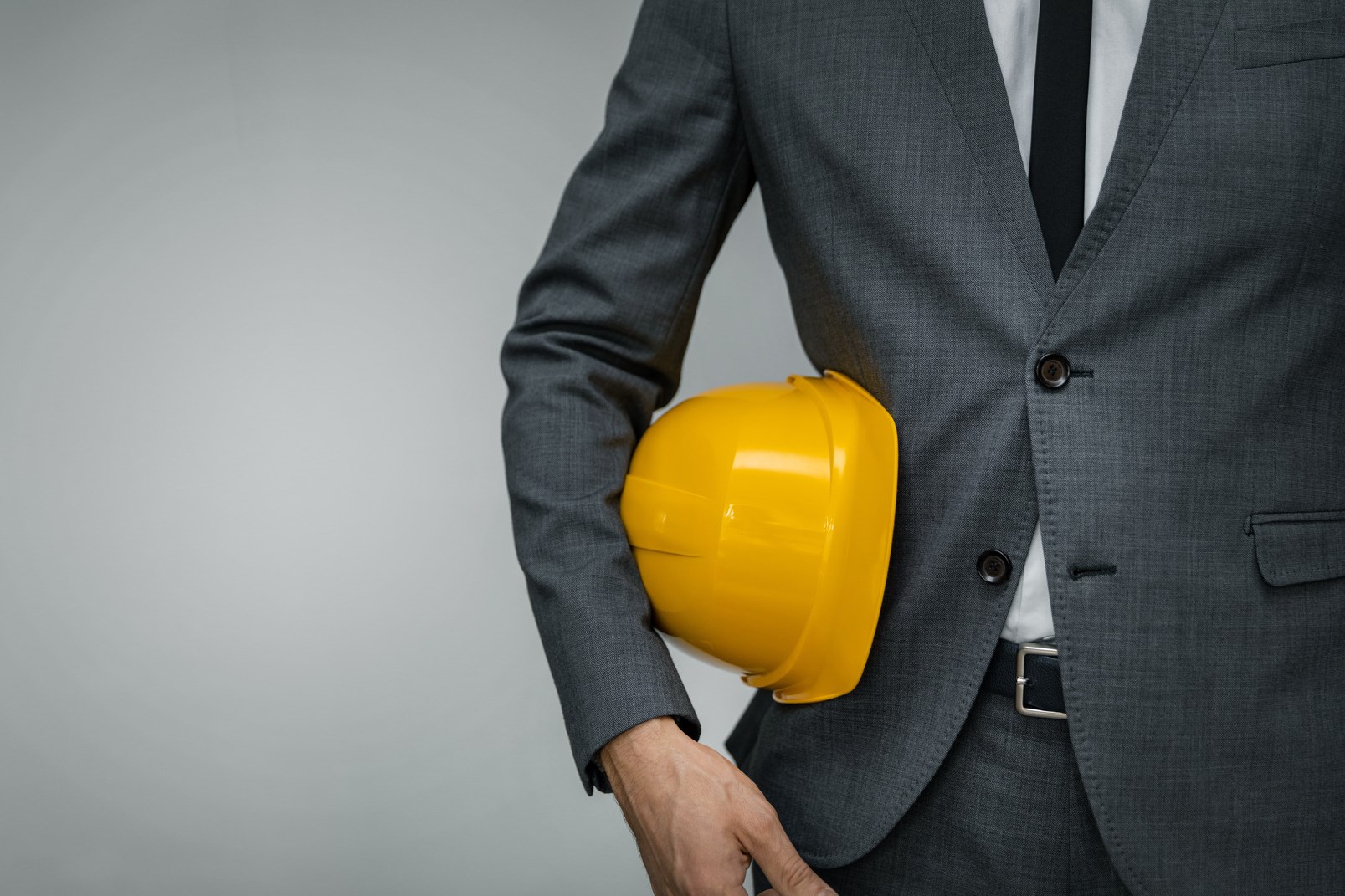 建筑行业业务-商人持有黄色安全帽腋下灰色背景与复制空间