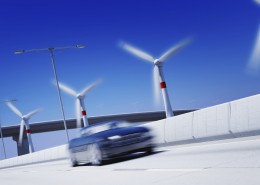 3D背景（运动模糊的车和涡轮机及焦背景）呈现绿色交通车超速的概念在公路上与风力涡轮机
